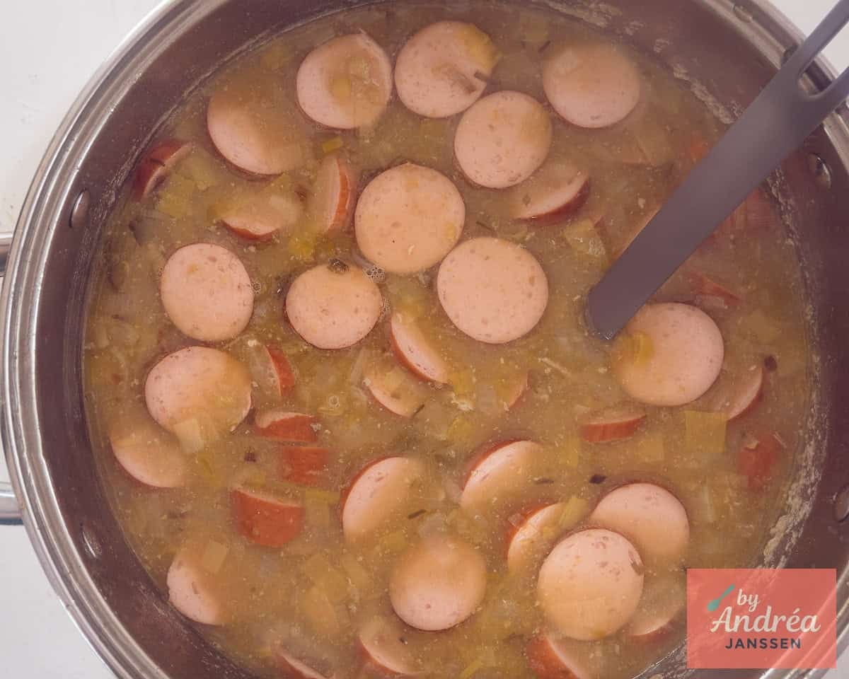 A pan of old-fashioned pea soup, sausage and ham on the stove