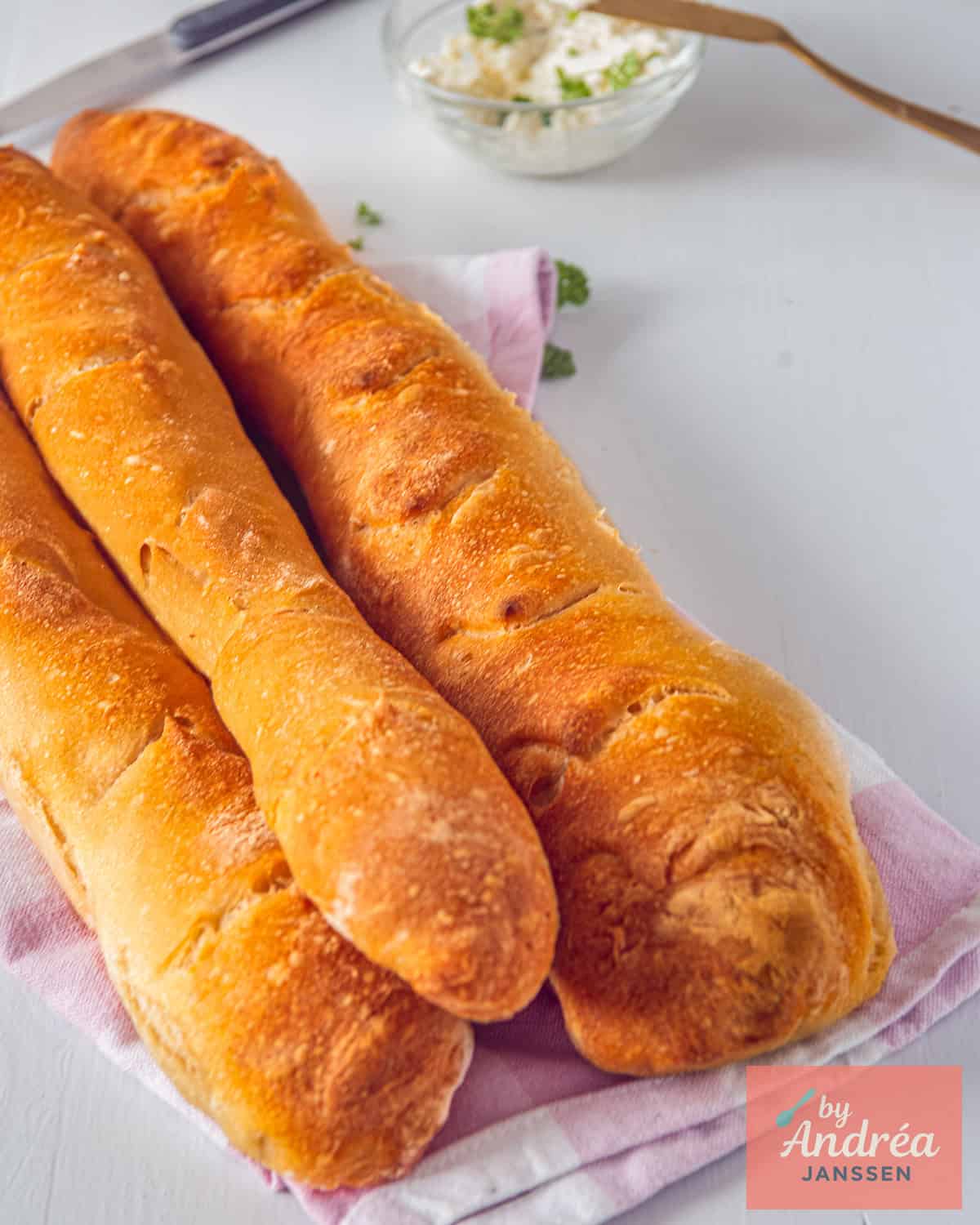 Three baguettes, homemade, on a tea towel.