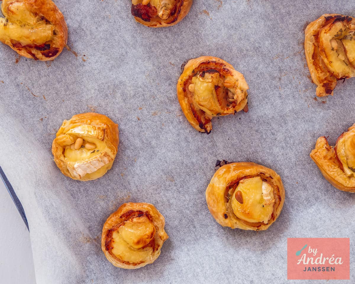 Baked puff pastry bites with cheese on a baking sheet