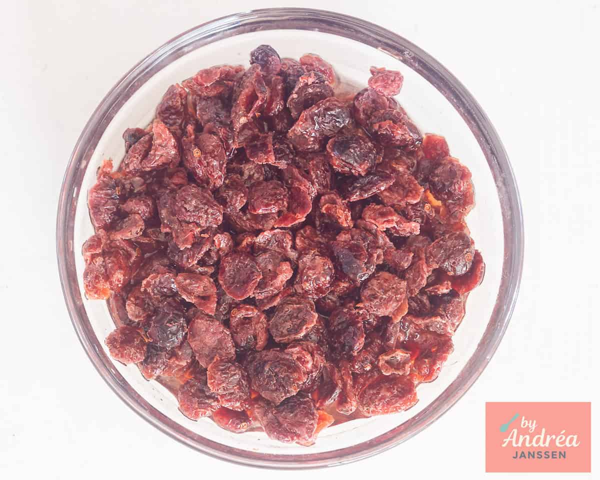Cranberries in a glass bowl soaking in apple juice.