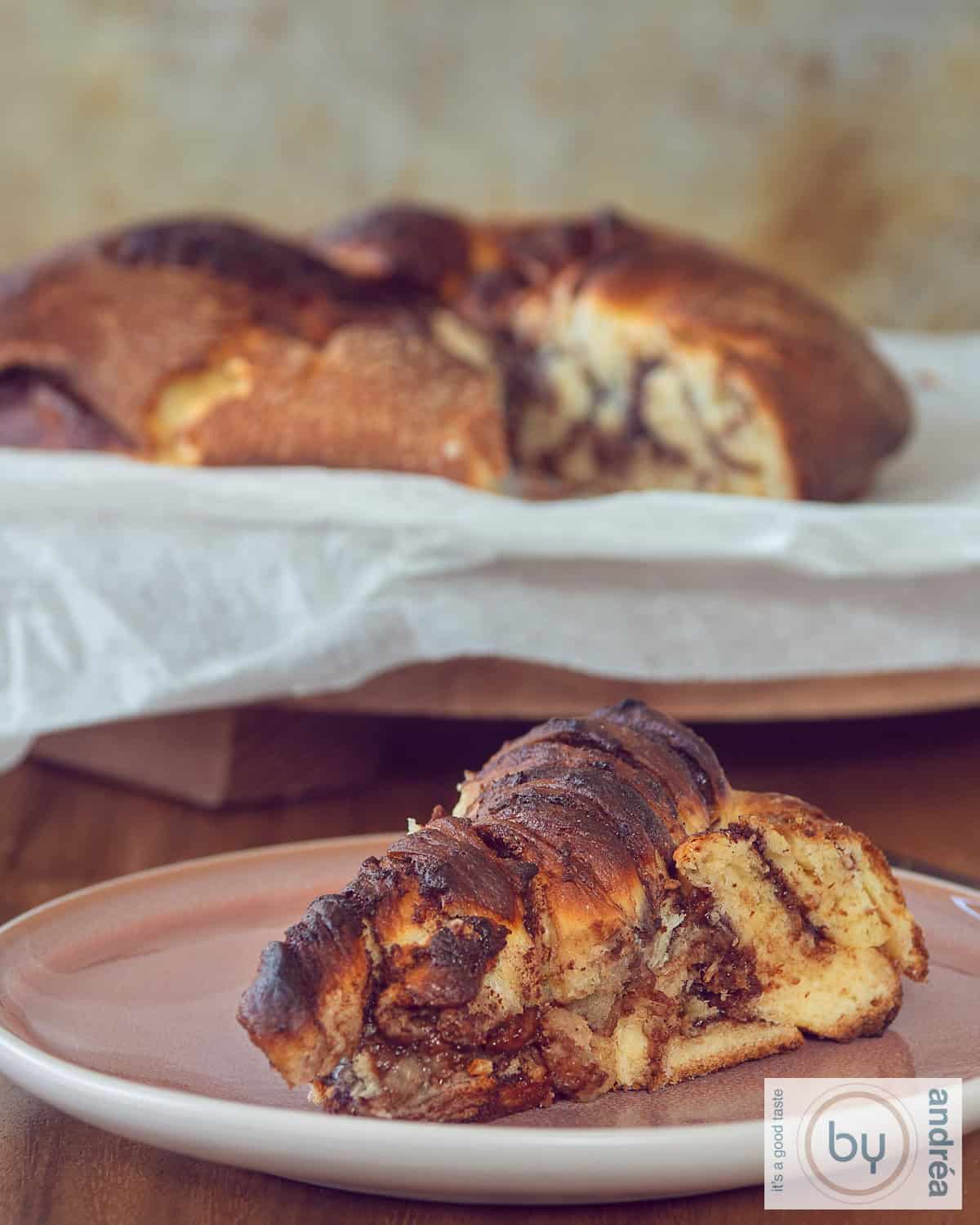 A pink plate with a slice of Nutella Twist Bread, homemade. Some more bread in the background.