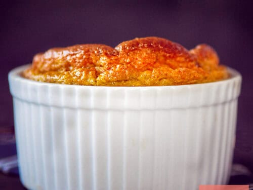 A square photo of a ramekin with a Jerusalem artichoke soufflé that has risen to the top.