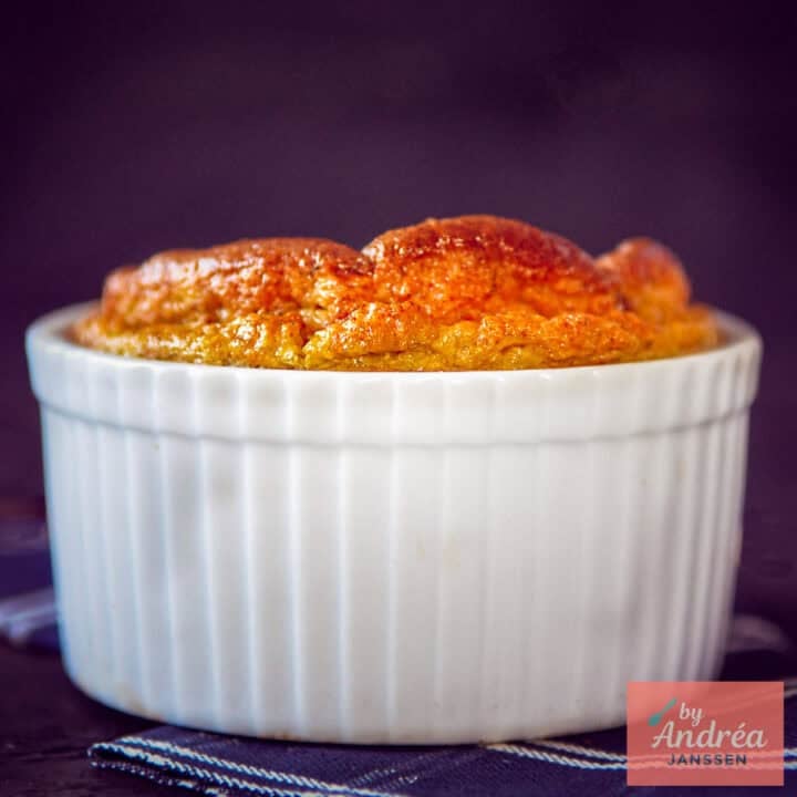 A square photo of a ramekin with a Jerusalem artichoke soufflé that has risen to the top.