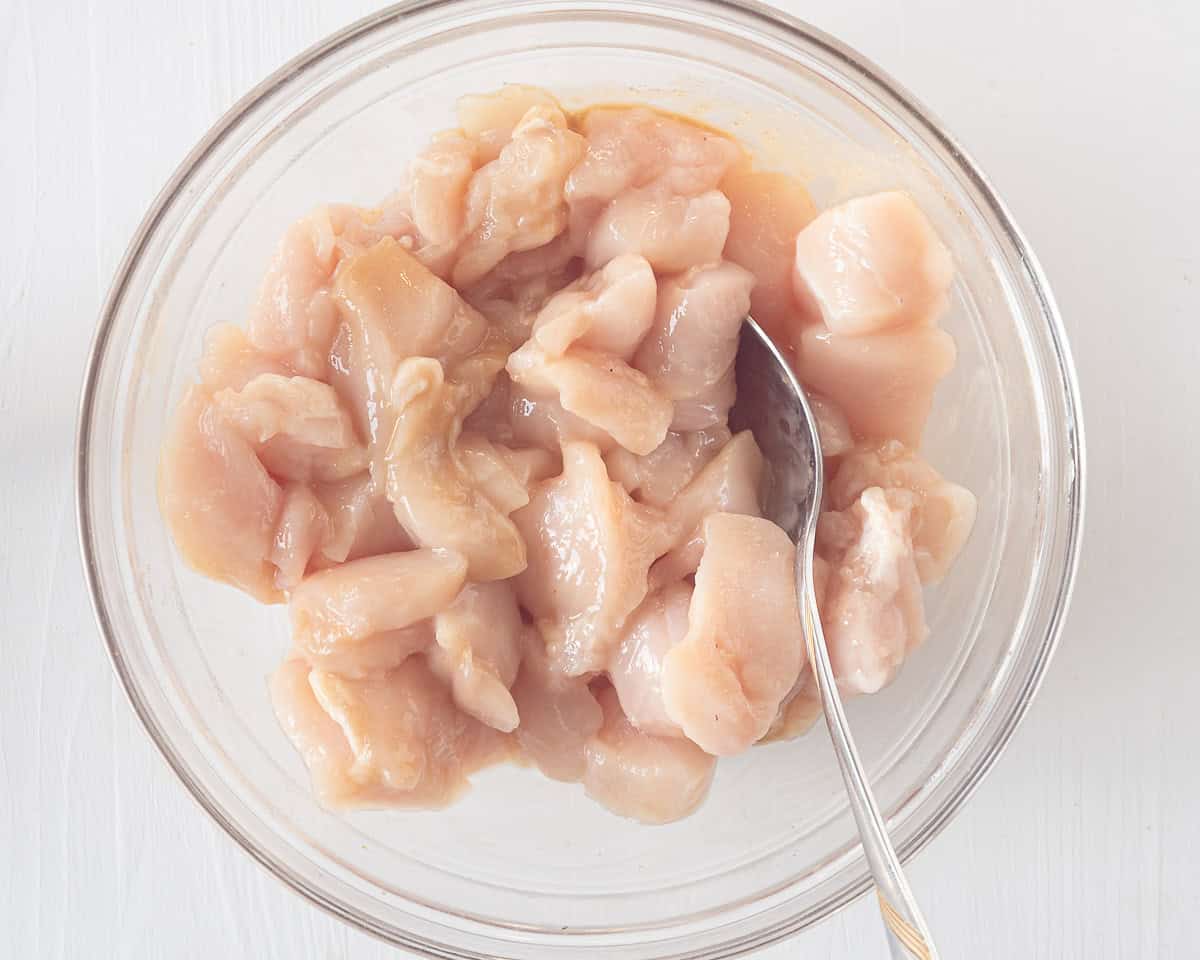 A bowl with chicken cubes that are covered with marinate.