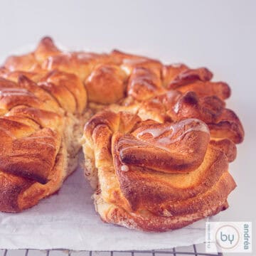 A square picture of part of a cinnamon star bread layered, with condensed mik drizzled on top.