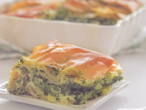 A square photo with several slices of savory pie with spinach and feta: spanakopita.