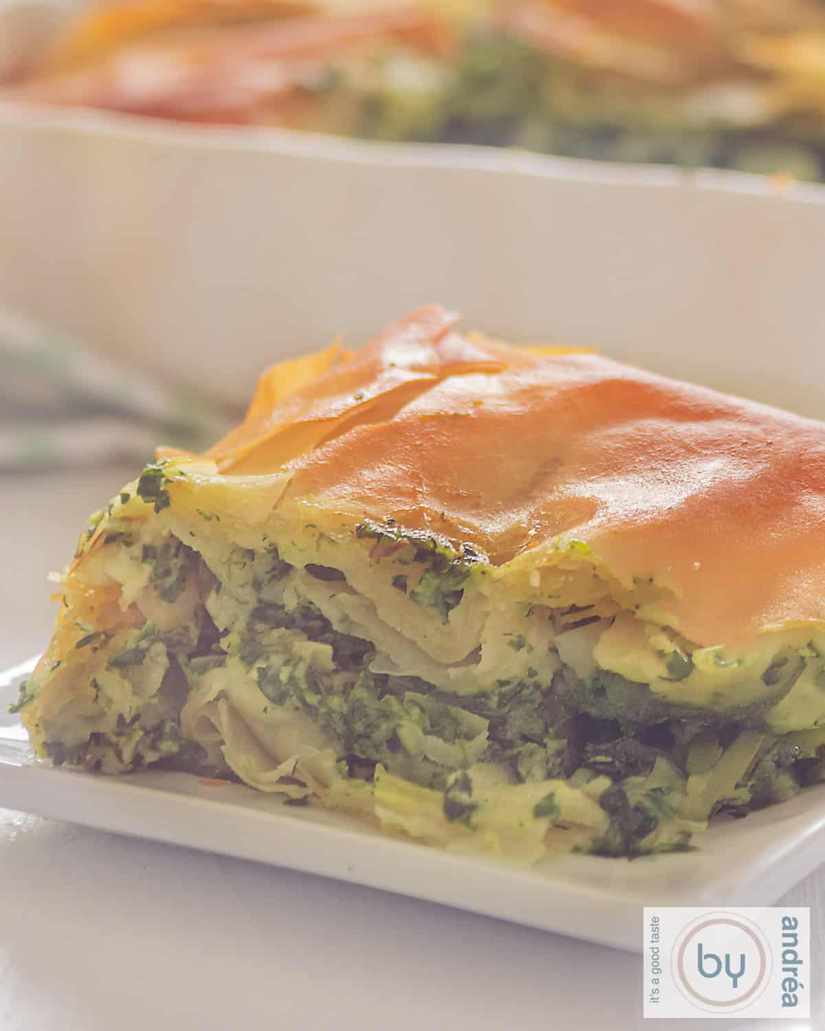 Een macro opname van spanakopita, griekse quiche op een wit bord.