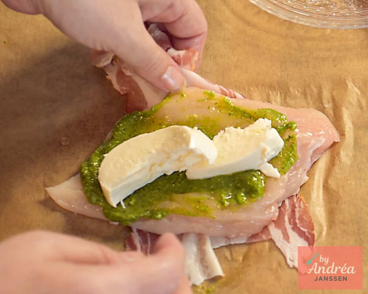 A chicken fillet cut open, spread with pesto and topped with mozzarella