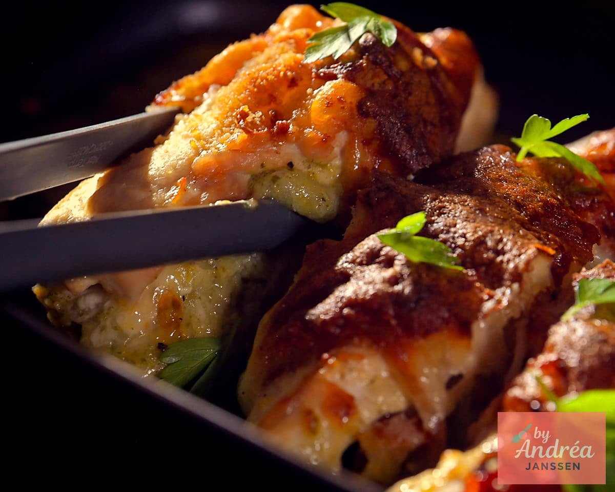 A wide photo of an oven dish in which a cooked chicken fillet filled with pesto and mozzarella is placed