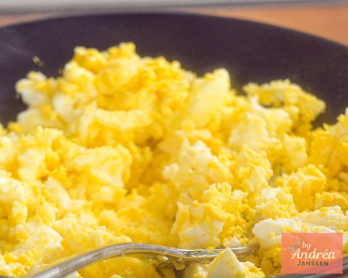 Mashed eggs in a black bowl.