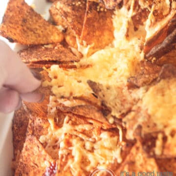 a part of a Mexican nacho casserole. A hand is taking a cheesy nacho cheese tortilla chips.