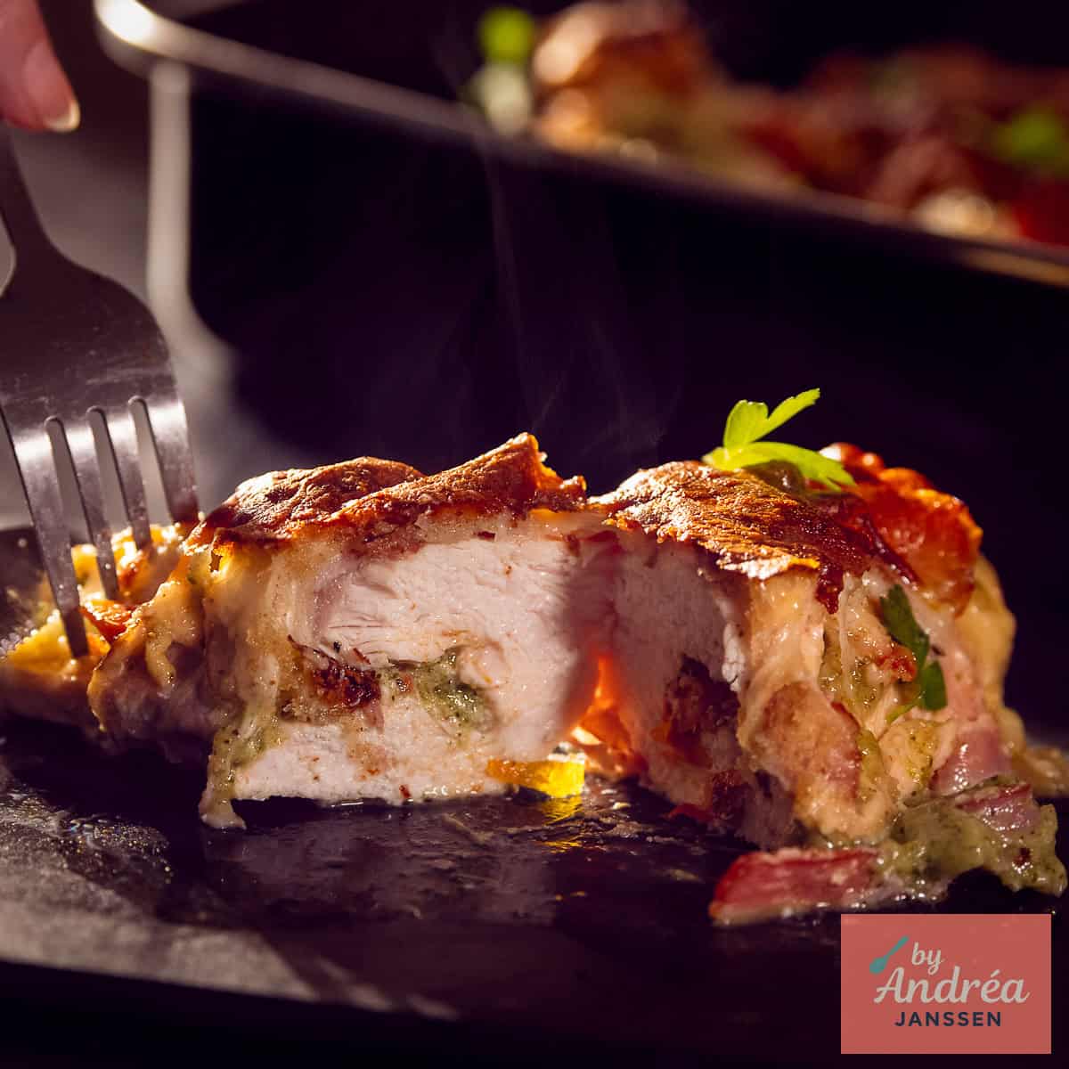 A square photo of a cut chicken fillet with pesto mozzarella filling