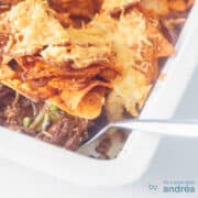 A square photo with a white baking dish with minced meat and vegetable filling (part of it can be seen) with nachos gratinated on top