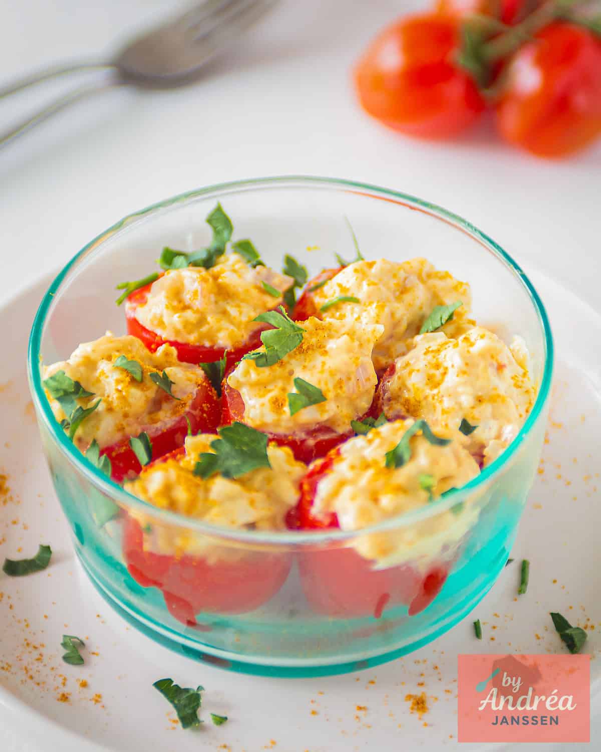 A blue glass container with 7 stuffed tomatoes with egg salad