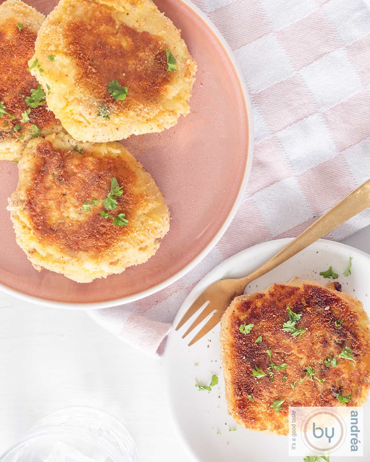Een foto van bovenaf van rechtsonderin een wit bord met een makreel visburger. Links bovenin ene roze bord met meer visburgers.