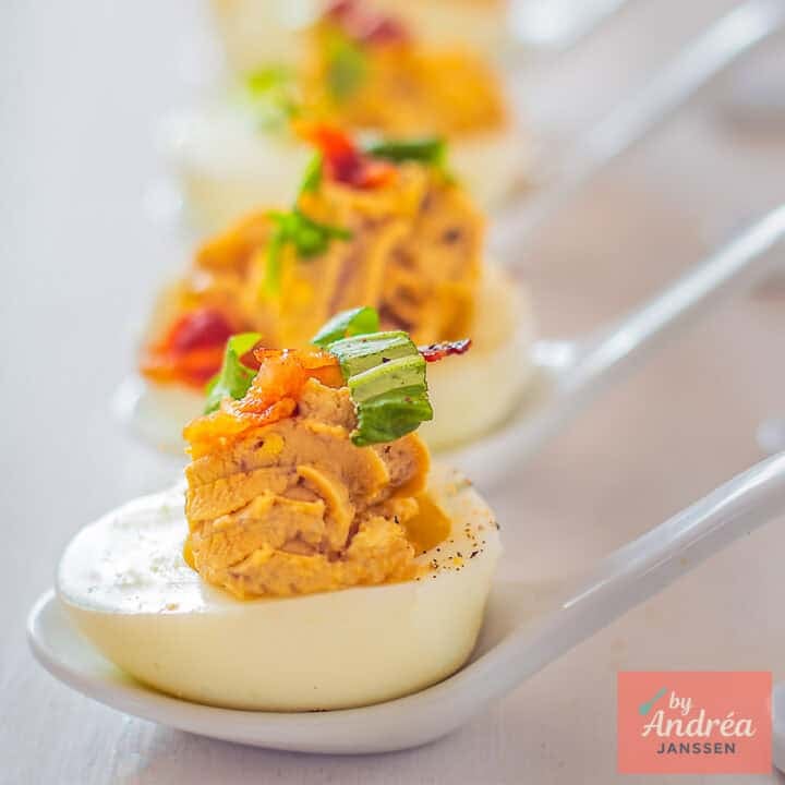 A square photo with a vertical row of Italian deviled eggs with balsamic and pancetta