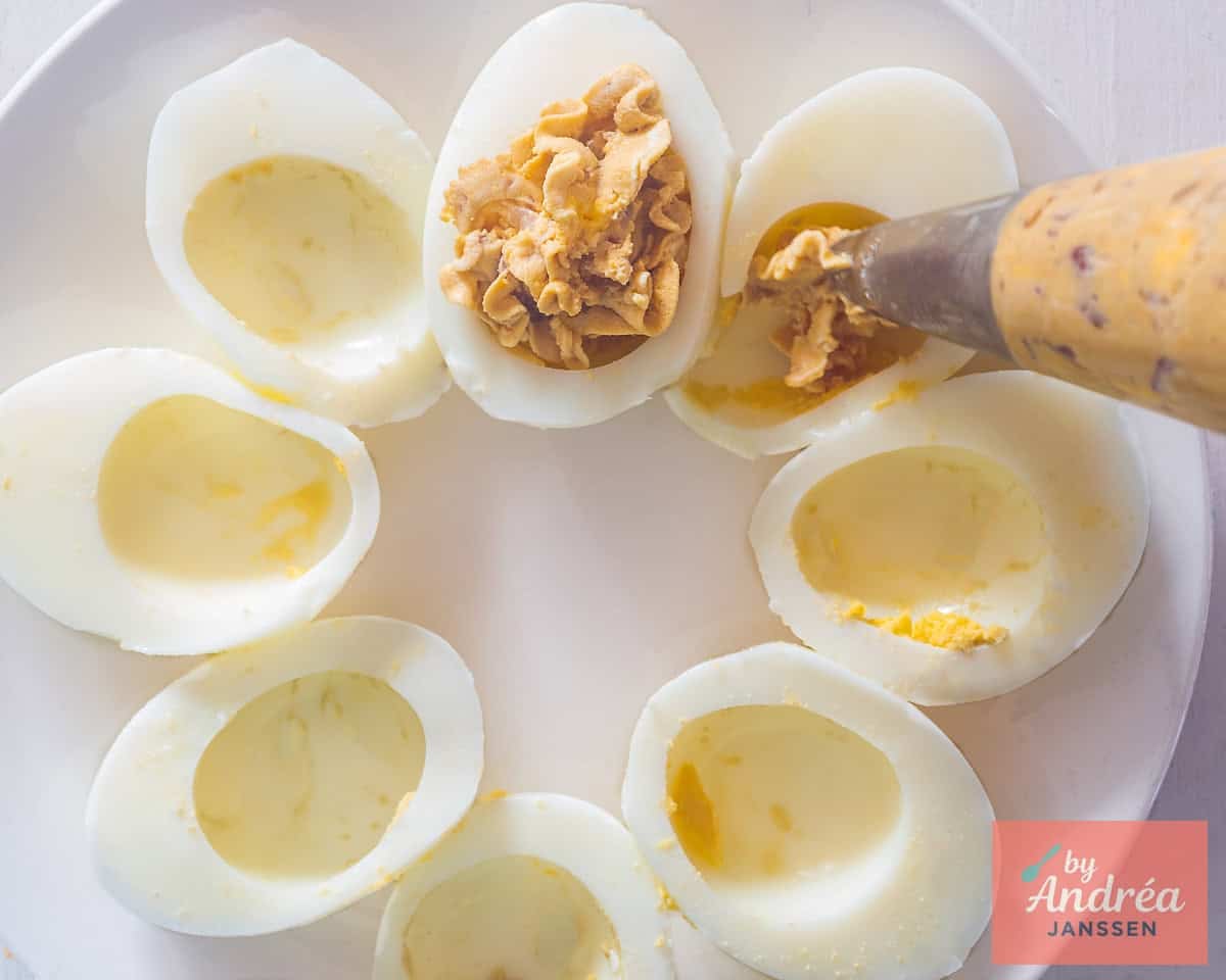 Fill the hollowed-out eggs with the filling using a piping bag.