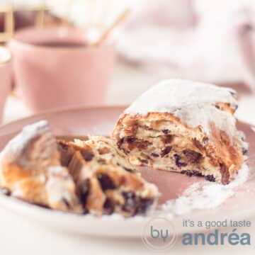 A square photo with an Easter stolly opened, so you see the inside with raisins, currants and orange. Background a pink cup with coffee and a bread basket.