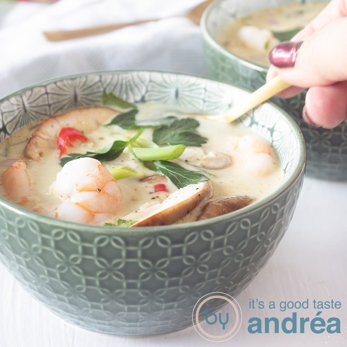 A square photo with a filled bowl with Thai coconut soup with shrimp.