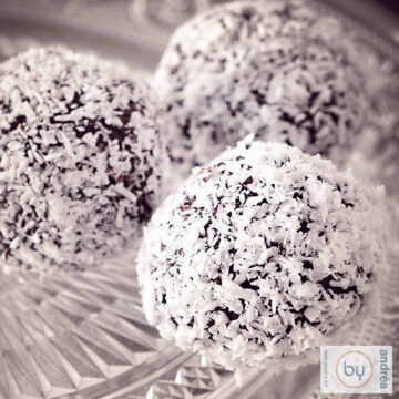 A square photo with three chocolate coconut truffles on a glass dish.