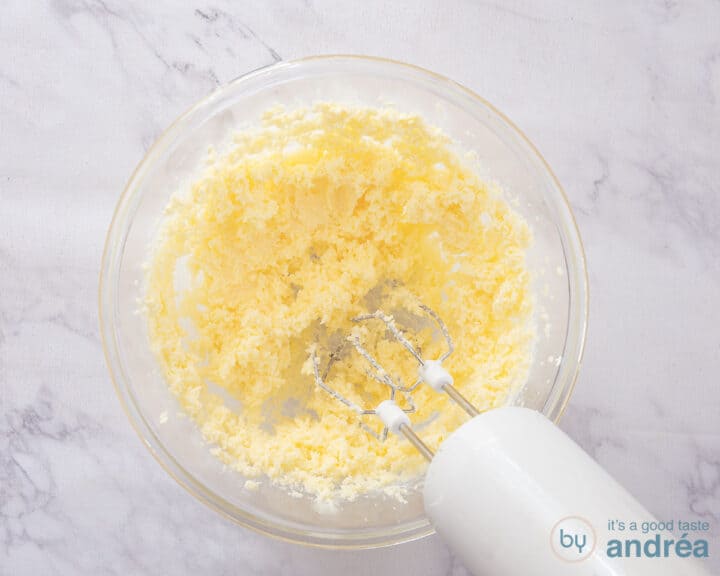 A glass bowl with a mix of butter and sugar.