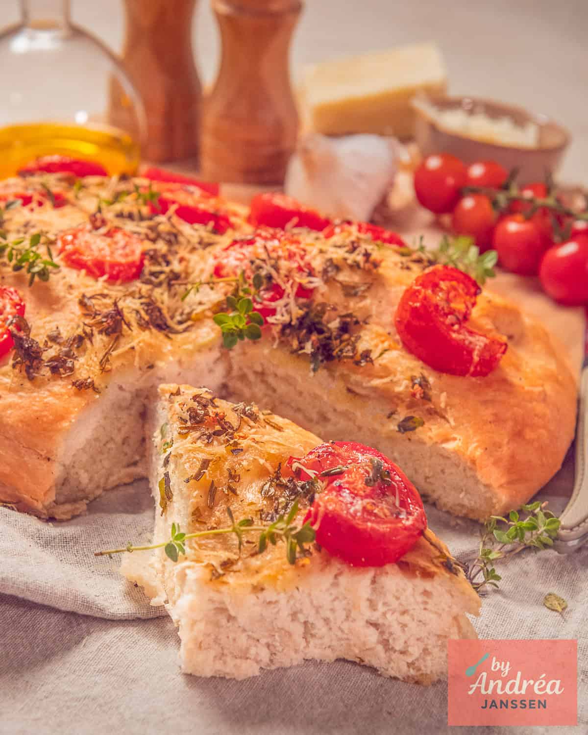 Een focaccia met tomaat, kruiden, knoflook en Parmezaanse kaas, een punt is er uitgesneden.