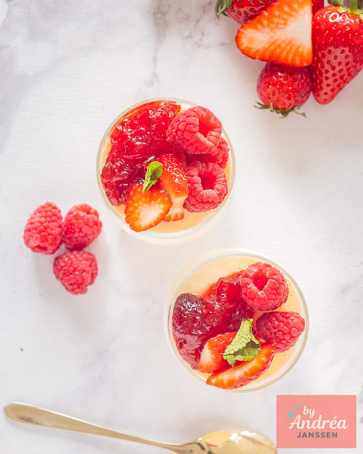 A photo from above of two small glasses with frozen yogurt ice cream, jam, and red fruit.