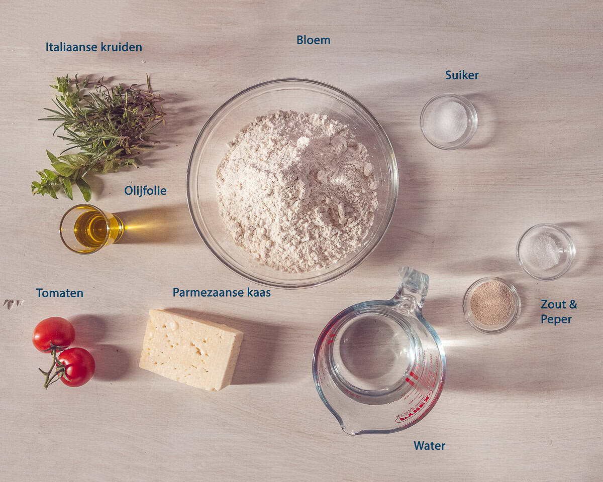 Ingredienten Focaccia met tomaat en Parmezaan op een beige ondergrond met tekstbeschrijving.