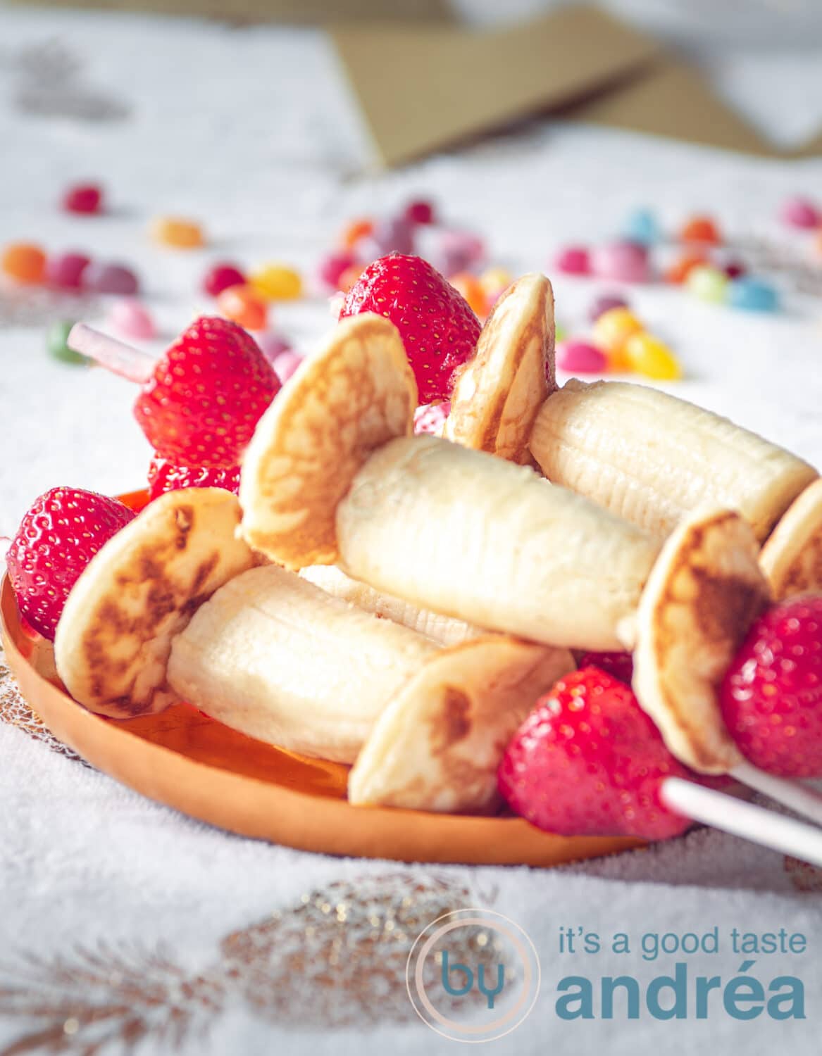 3 healthy treats with banana strawberries and pancakes on a stick on a plate