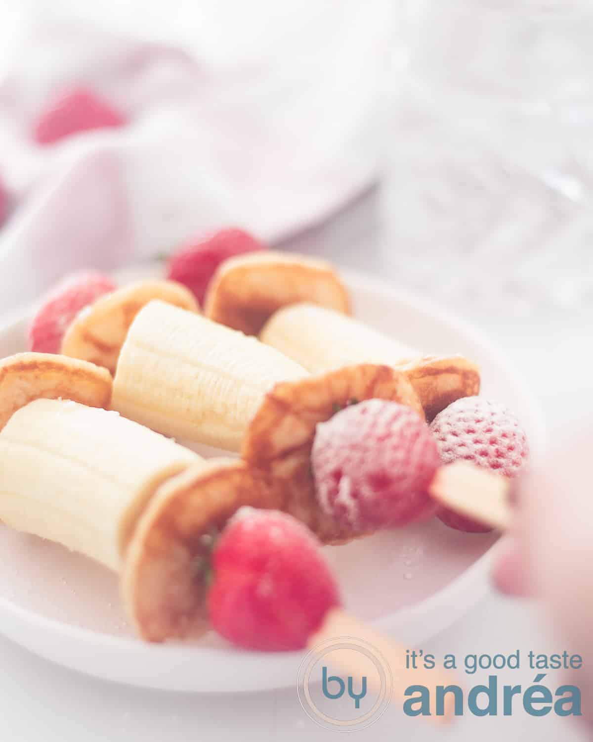 3 healthy treats with banana strawberries and pancakes on a stick on a plate
