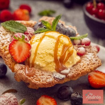 A square photo with a cookie cup containing vanilla ice cream with caramel sauce and fruit.