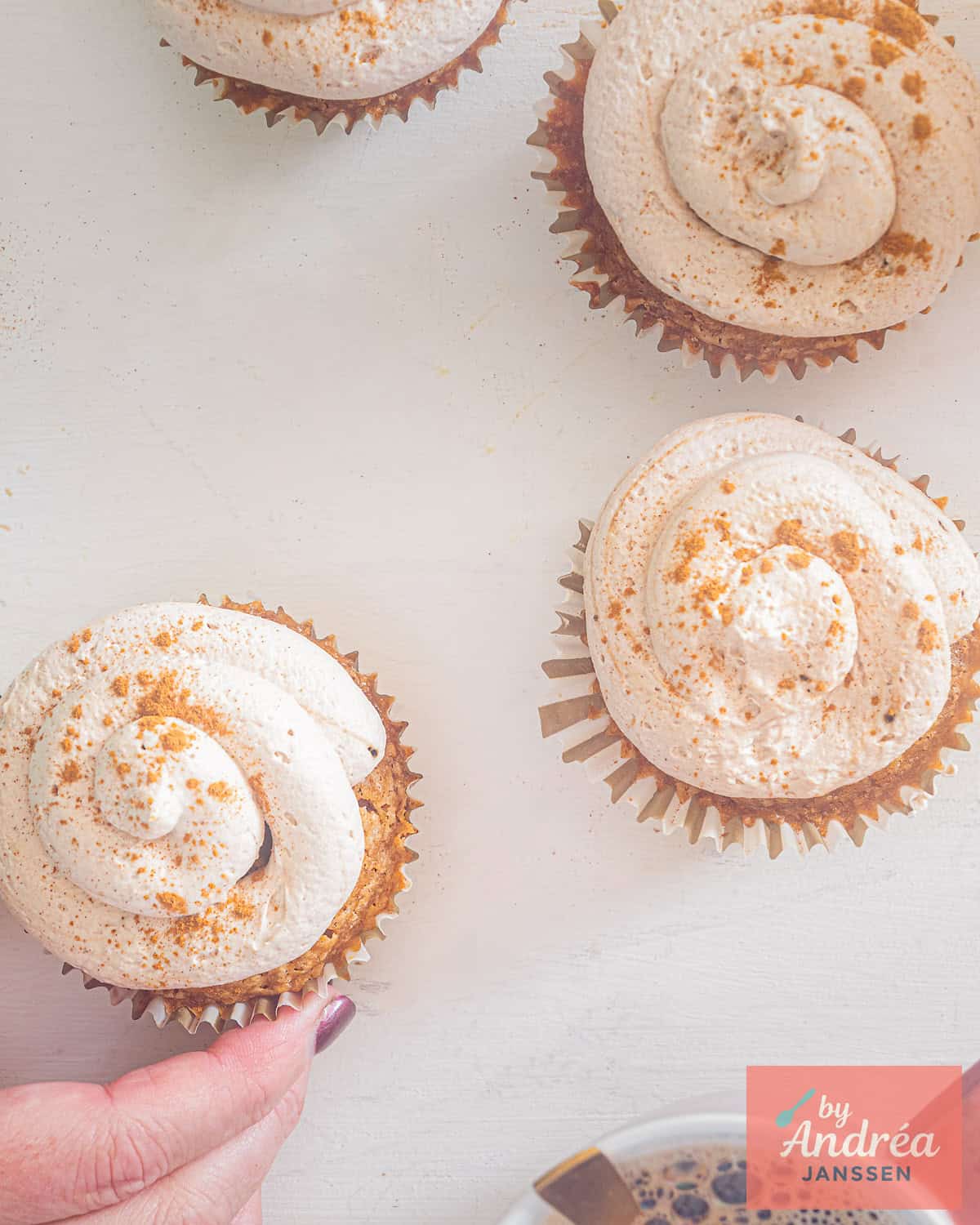 A picture from above of several tiramisu cupcakes. A hand is taking one