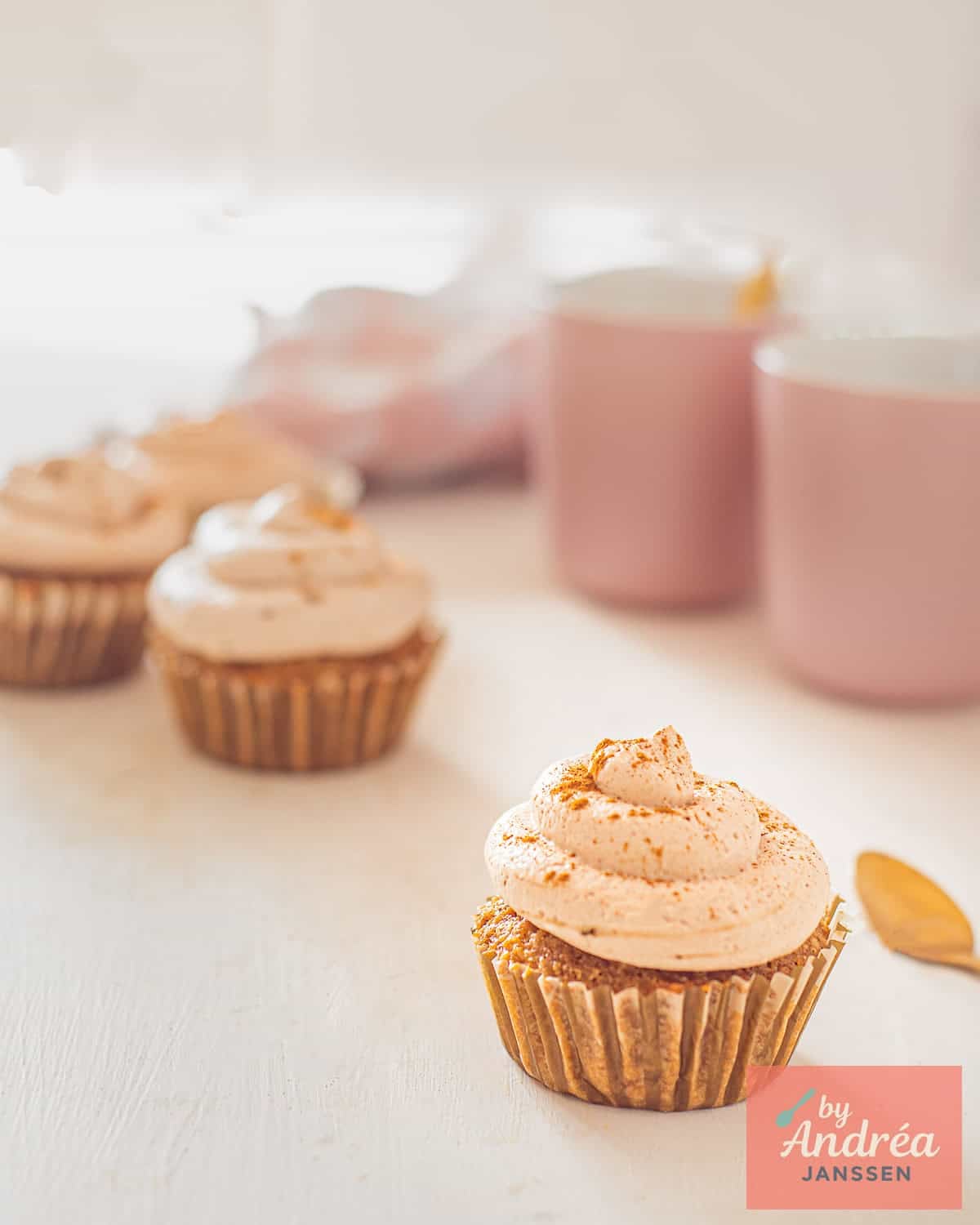 In front a tiramisu cupcake in the back several more and some coffee cups.