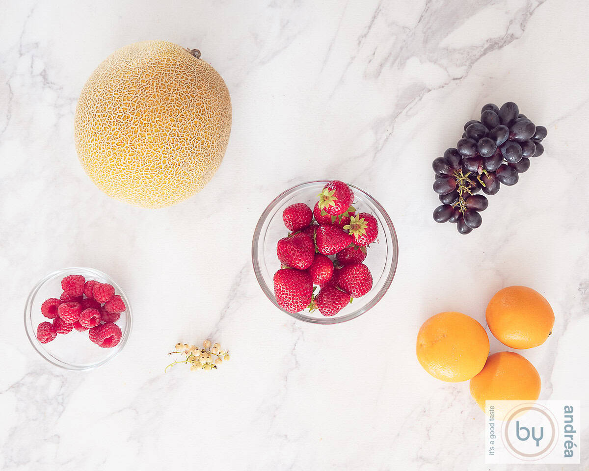 Ingrediënten voor een vrolijke fruitsalade op een marmeren ondergrond