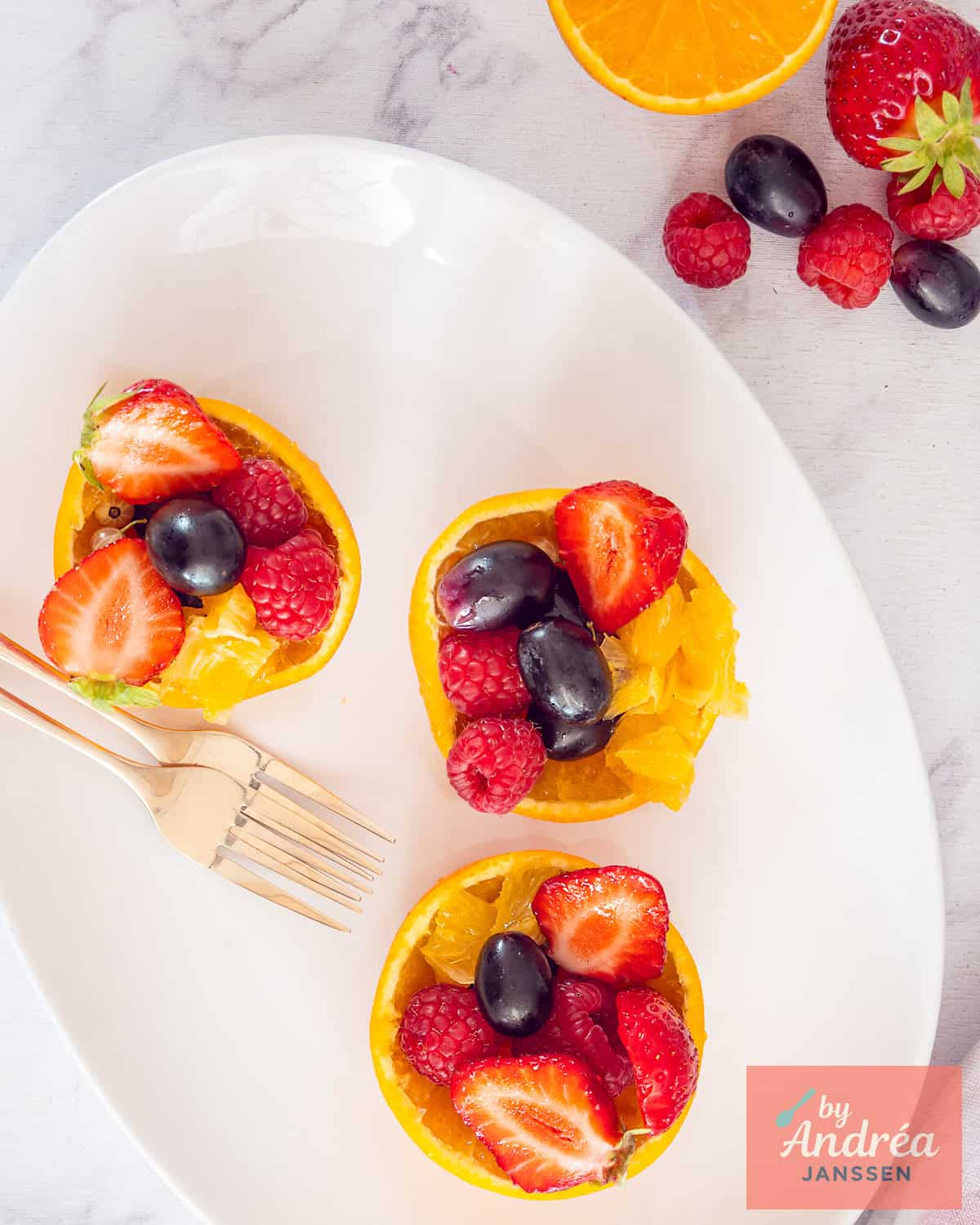 A top down picture of orange fruit cups filled with fresh fruit