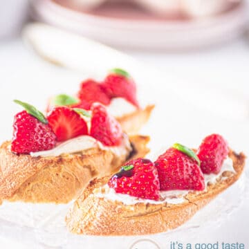 two bruschetta with marinated strawberries and mascarpone and some plates in the back