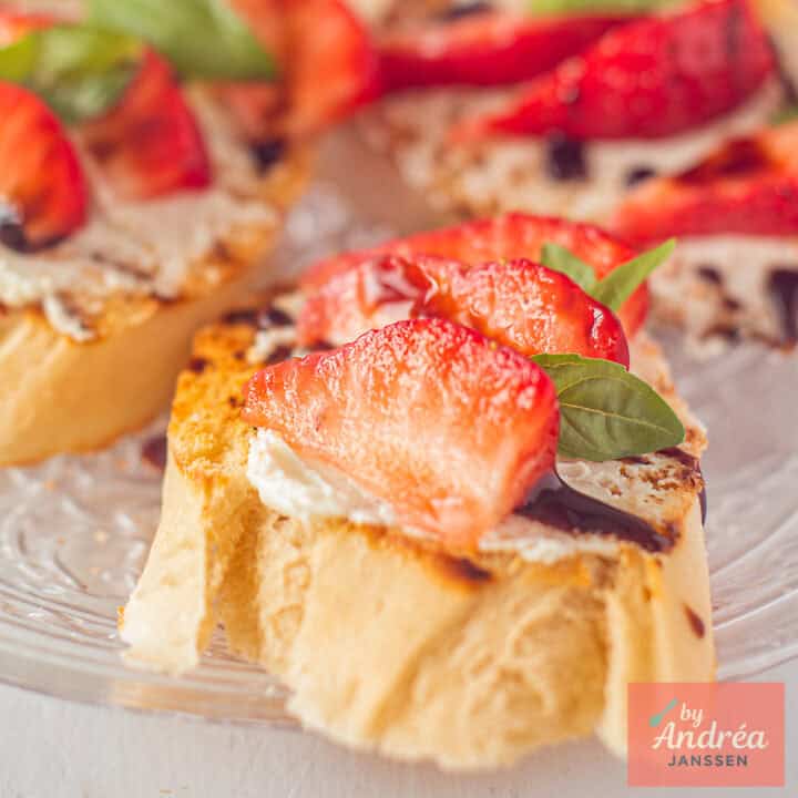 Een vierkante foto met een aardbeien bruschetta met mascarpone, balsamico en basilicum