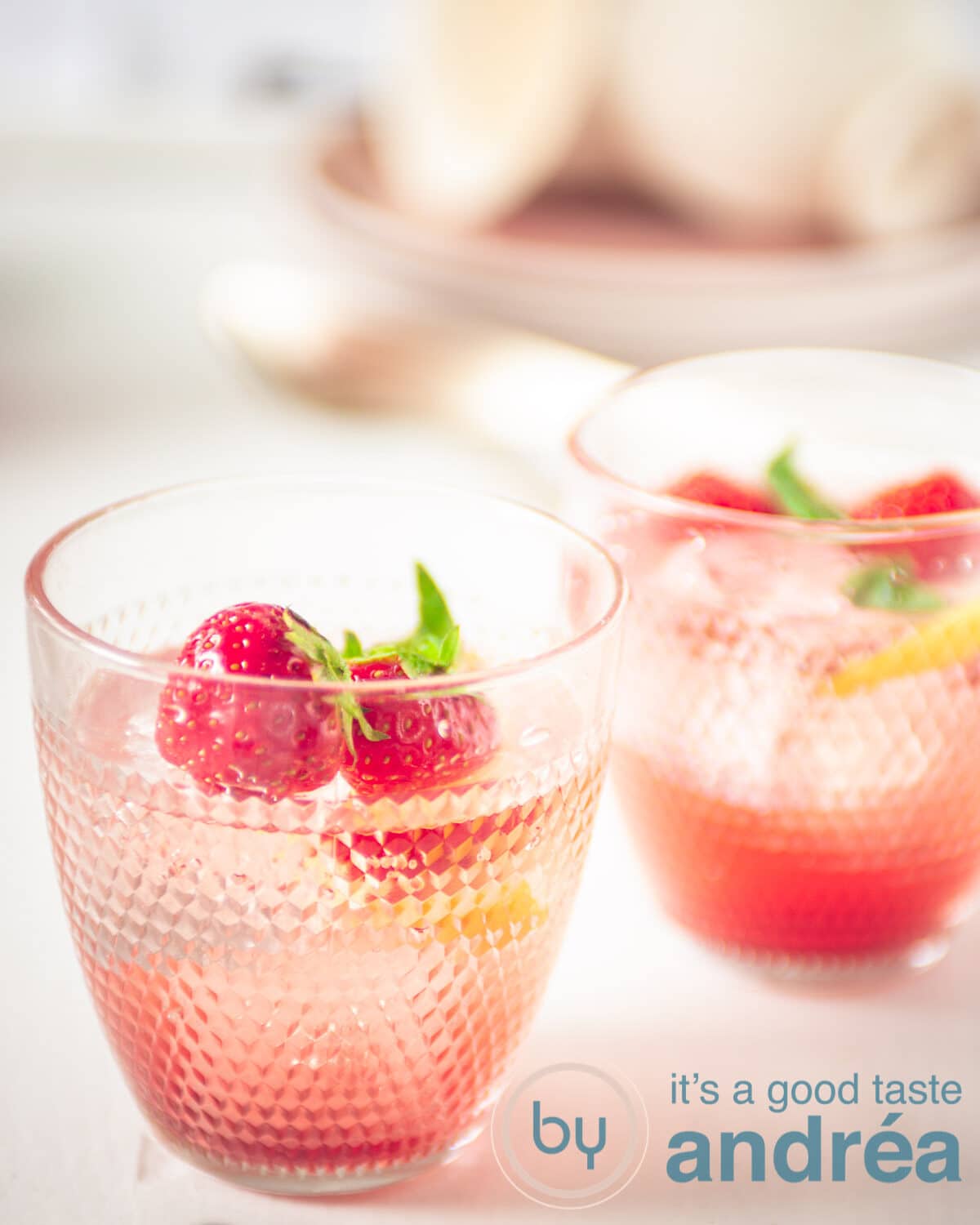 two glasses of strawberry lemonade with strawberry and lemon garnish
