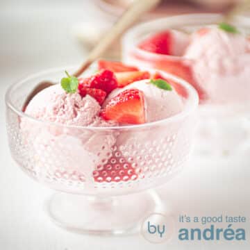 A square photo with two glass bowls filled with strawberry ice cream balls, fresh strawberries and mint.