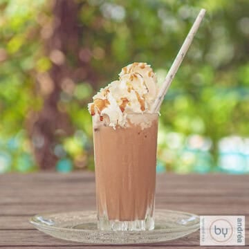 A square photo of a frappuccino on a wooden table.