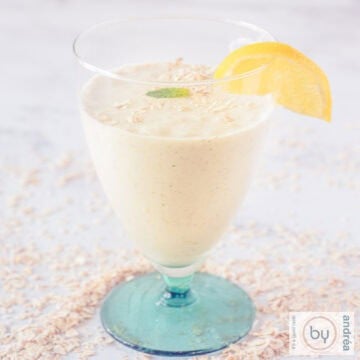 A square picture with a glass with a green feet filled with banana oatmeal and mint.