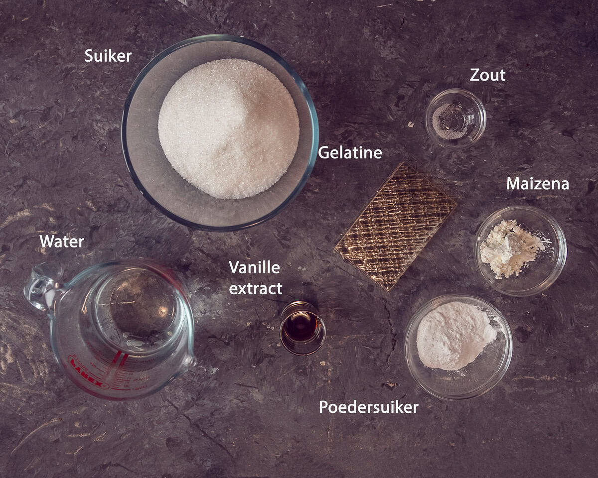 Ingredienten S'mores met Zelfgemaakte Marshmallows op een grijze ondergrond met tekstbeschrijving.