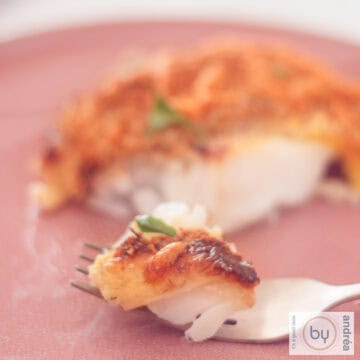 A square picture with cod with a cheese breadcrumb topping. A fork took a bite.