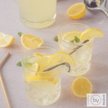 A square picture of two glasses of lemonade with vanilla and lemon and mint.