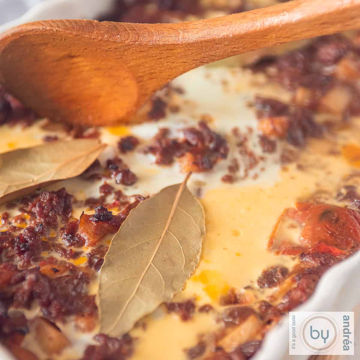 A square photo of a bobotie casserole with minced meat, bay leaves, egg, apple and raisins.