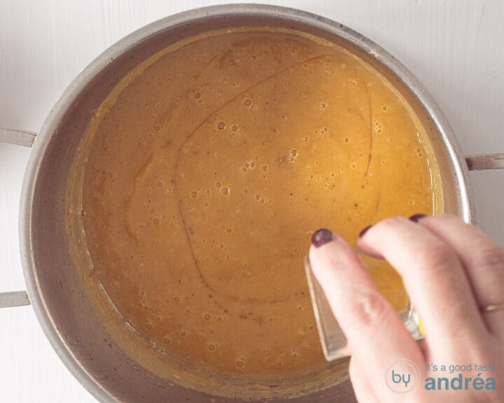 Maple syrup is added to the pan of pumpkin soup.