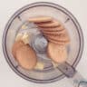 A food processor bowl with cookies and white chocolate.