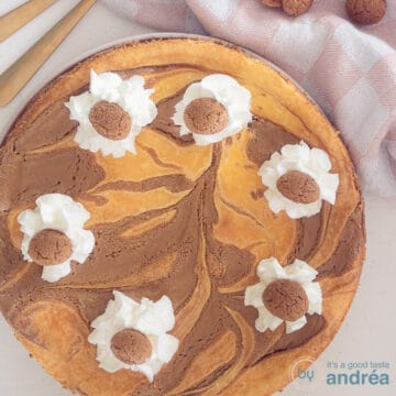 A square photo with a cheesecake with spiced nuts, Speculoos and whipped cream. A white background