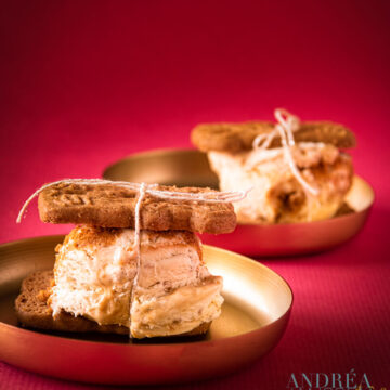 Ice cream with chocolate and caramel between two cookies on golden plates