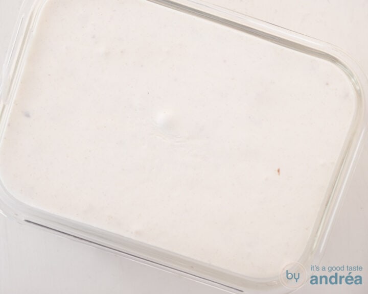 The ice cream is poured into a glass freezer container.